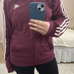 Adidas tröja - Mörkröd/ lila adidas zip hoodie. Nypris runt 500-600kr. Använd 3-4 gånger, storlek M. Vid frågor är de bara att skriva.