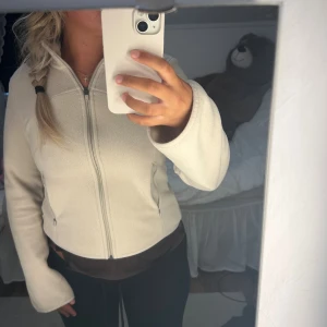 Beige fleecejacka från H&M Move XS - Mysig beige fleecejacka från H&M Move i storlek XS. Jackan har dragkedja framtill, två sidofickor med dragkedja och långärmade ärmar. Perfekt för kyliga dagar och enkel att matcha med dina favoritjeans eller leggings.