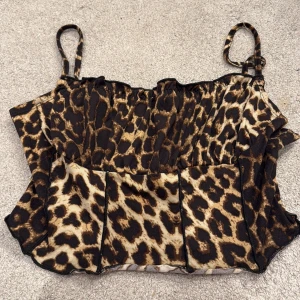 Leopardmönstrad korsett-topp - Säljer en snygg leopardmönstrad korsett-topp med smala axelband och figurnära passform. Toppen har bruna och beige toner och är tillverkad i ett stretchigt syntetmaterial. Perfekt för dig som vill sticka ut med ett djurmönster och trendig look.