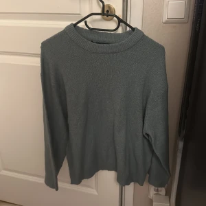 Grå stickad tröja med rund hals - En enkel och stilren grå stickad tröja med rundad hals och långa ärmar. Perfekt för dig som gillar en clean look och vill ha något mjukt och bekvämt att slänga på dig när det är lite kyligt ute.