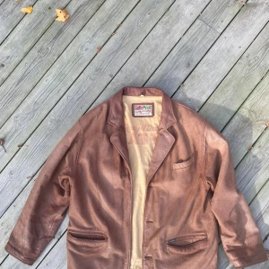 Vintage läderjacka 80-tal - En brun vintage läderjacka troligtvis från 80-talet. Jackan har väldigt mycket patina men inte några hål i lädret. Finns defekter inuti i tyget men inget som påverkar jackans funktion, knapparna saknas. Riktigt cool om du vill ha något unikt.