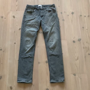 Regular jeans - Säljer ett par grå jeans från Jack & Jones, modell Regular Clark. Klassisk femficksdesign, raka ben och normal passform. Jeansen är i bomull och har en snygg, neutral grå färg som passar till det mesta. Perfekta för dig som gillar enkel och stilren look.