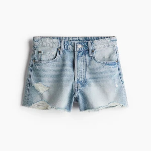Ljusblå jeansshorts från H&M - Säljer ett par ljusblå jeansshorts från H&M i klassisk femficksmodell. Shortsen har slitna detaljer, råa kanter och en avslappnad passform. Perfekta för varma dagar och ger en cool, avslappnad vibe.