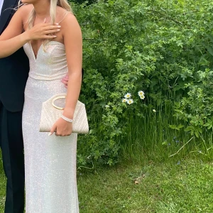 Balklänning - INTRESSEKOLL!!                      Supersnygg balklänning med v-ringning. Klänningen är axelbandslös, Perfekt för bal. Säljes då jag inte längre har användning för den! Jag är 165cm lång och har klackar på bilderna som är några cm höga. Köpte klänningen ny ifrån Asos och klänningen använd 1gång dvs inprincip nyskick! Klänningen är insydd i midjan någon centimeter hos skräddare just för att klänningen skulle sitta på plats, alltså knappast något skillnad. Skriv vid frågor eller intresse! 