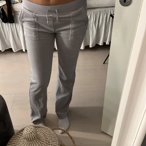 Grå mjukisbyxor med snörning - Snygga grå mjukisbyxor med bred resår i midjan och snörning framtill. Byxorna har stora fickor fram och bakfickor med lock och tryckknappar. Sköna och stilrena, perfekta för chill dagar.