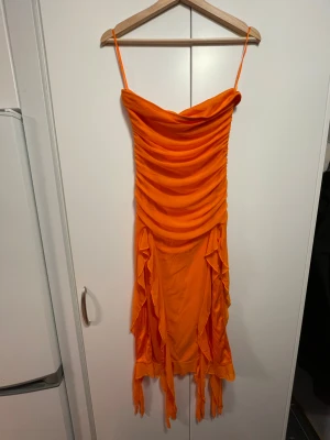orange stretchig tubklänning - orange, åtsittande, axelbandslös klänning med volanger från shein! klänningen har två öppningar vid benen och ribbade detaljer vid midjan. aldrig använd, endast testad