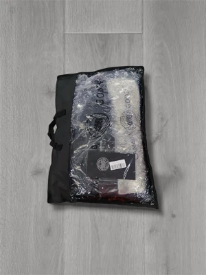  Canada Goose Wyndham Red label - Svart dunjacka från Canada Goose med avtagbar huva och pälsdetalj. Jackan har puffad design, knappar och dragkedja framtill samt klassisk logotyp på ärmen. Perfekt för kalla vinterdagar och har en clean, modern look.