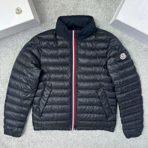 Svart dunjacka från Moncler - Säljer en svart dunjacka från Moncler med klassisk quiltad design och ståkrage. Jackan har en snygg dragkedja med röd, vit och blå detalj samt Moncler-logga på ärmen. Perfekt för kyliga dagar och har två sidofickor med dragkedja.