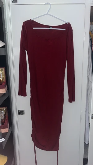 Vinröd långärmad klänning från SHEIN - Säljer en vinröd långärmad klänning från SHEIN i storlek M. Klänningen har en tight passform, rund halsringning och snörning längst ner på sidorna. Materialet är mjukt och stretchigt, perfekt för dig som gillar stilrena och enkla plagg.