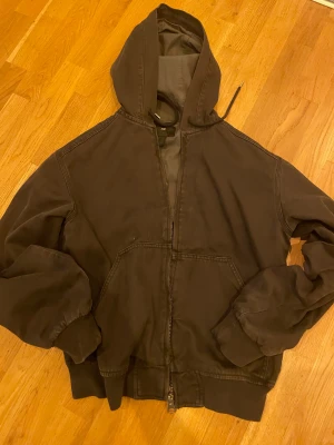 Svart active jacka från H&M - Säljer en svart hoodie active jacka från H&M med dragkedja framtill och två stora fickor. Jackan har ribbade muddar vid ärmslut och nederkant samt en stor huva med snörning. Perfekt för chill dagar och streetwear.