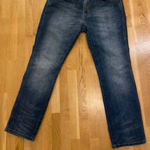 Wrangler Greensboro blå jeans - Snygga Wrangler Greensboro jeans i mörkblå tvätt med klassiska kontrastsömmar och raka ben. Jeansen har en bakficka med broderad detalj och är tillverkade av 73% bomull och 25% polyester. Perfekt för dig som gillar en tidlös och chill look.