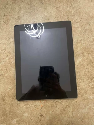 Apple iPad (2:a generationen) - Apple iPad 2 med 9,7-tums skärm, silverfärgad baksida och svart front. Skicket är begagnat med mindre yttre slitage, men inga större repor eller sprickor synliga. Perfekt för surf, appar och media. Klassisk design med hemknapp och kamera på baksidan.