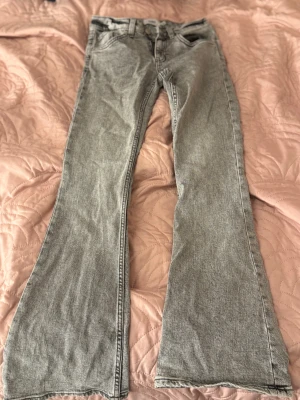 Grå bootcut jeans XS - Säljer ett par grå jeans från lager157 i storlek XS. Modellen har bootcut-snitt som ger en schysst siluett. Jeansen är tillverkade i jeansmaterial och har dragkedja och knapp framtill.
