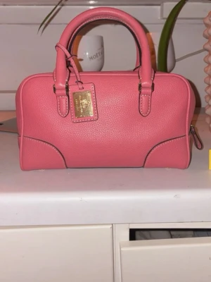 Rosa handväska från Ralph Lauren - Säljer en snygg rosa handväska från Ralph Lauren med guldiga detaljer. Väskan är från en sample sale och är svår att få tag på därav priset. (Priset går att diskutera) skriv privat för fler bilder 