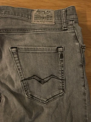Replay grå jeans straight fit - Snygga grå jeans från Replay med klassisk femficksdesign och raka ben. Jeansen har svarta detaljer på bakfickan och Replay-logga vid myntfickan. Materialet är slitstarkt jeans och passformen är normal med straight fit.