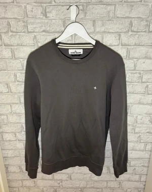Stone Island tröja - Stone Island sweatshirt med rund hals och diskret vit stjärnlogga på bröstet. Tröjan har långa ärmar, ribbade muddar och är tillverkad i mjuk bomull. Perfekt för dig som gillar stilrena och klassiska plagg med enkel logga. Hör av dig vid intresse 🙌