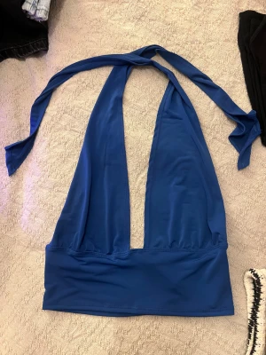 Blå omlott linnetopp från NLY One - Säljer en snygg blå omlott linnetopp från NLY One i storlek M. Toppen har breda band som knyts i nacken och en djup urringning framtill. Materialet är mjukt och stretchigt, perfekt för att skapa en cool och trendig look.