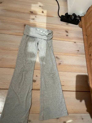 Grå bootcut mjukisbyxor från H&M - Snygga ljusgrå mjukisbyxor från H&M i storlek 140. Byxorna har bootcut-ben och bred, vikbar midja för extra komfort. Tillverkade i mjukt bomullsmaterial som är perfekt för chill dagar. Enkla att matcha med hoodies eller t-shirts.
