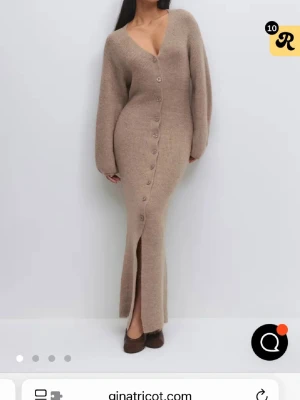 Beige stickad långklänning Gina Tricot - Supermysig beige stickad långklänning med v-ringning och knappar hela vägen framtill. Klänningen har långa, lite puffiga ärmar och en slits nertill. Perfekt för dig som gillar en slim och figurnära passform med snygga detaljer. Använd en gång❤️