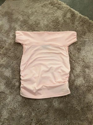 Ljusrosa bandeau tubtopp - Säljer en ljusrosa bandeau tubtopp med axelbandslös design.