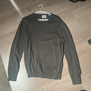 Mörkgrön stickad tröja från Bläck - Snygg mörkgrön tröja från Bläck i storlek M. Tröjan har rund hals, ribbade muddar vid ärmslut och nederkant samt långärmad passform. Perfekt för dig som gillar stilrena och enkla plagg med skön känsla. Nypris; 800kr