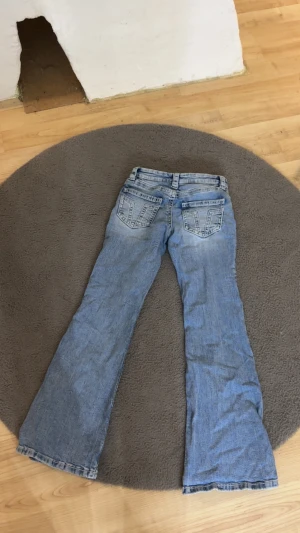 Blå bootcut jeans Gina Young  - Säljer ett par blå bootcut . Jeansen har klassiska fem fickor, bälteshällor och dragkedja med knapp. Bakfickorna har dekorativa sömmar som ger extra stil. Perfekt för dig som gillar retrovibbar och avslappnad look. Aldrig använda 