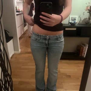 Ljusblå bootcut jeans från Lee - Säljer ett par ljusblå jeans från Lee med bootcut passform och låg midja. Klassisk femficksmodell med Lee-lapp bak i brunt skinn. Jeansen har en snygg tvätt och är gjorda i mjukt jeanstyg med dragkedja och knapp framtill. AS SNYGGA