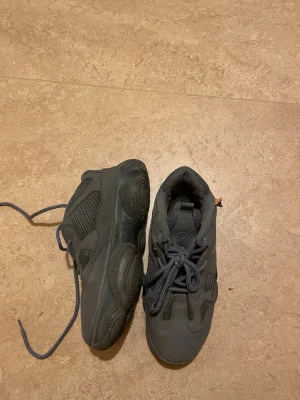 Svarta chunky sneakers med snörning - Säljer ett par svarta chunky sneakers med grov sula och snygga meshpaneler. Skorna har rund tå och snörning framtill. Perfekta för dig som gillar streetstyle och vill ha en cool look. Materialet är syntet och mesh för bra ventilation.