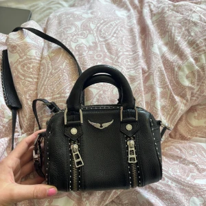 Svart handväska från Zadig & Voltaire - Svart väska i skinn från Zadig & Voltaire, stoleken nano. Väskan är knappt använd och i topp skick! Dustbag och äkthetsbevis finns! 