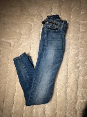 Blå Replay jeans straight fit - Snygga blå jeans från Replay med klassisk femficksdesign och raka ben. Jeansen har en ljus tvätt med subtila slitningar och detaljer som dragkedja i gylfen. Perfekt passform för dig som gillar en tidlös look.