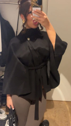 Svart kappa med bälte och knapp - Säljer min fina kappa Och  knappen  vid halsen är SILVER Inte guld den va guld innan men färgen är borta så knappen är Silver finns ingen storlek på kappan !!❤️❤️