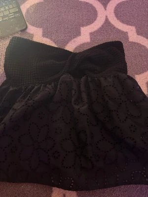 Svart strapless topp - Supersöt svart bandeau tubtopp med smockad överdel och broderade blommor på tyget. Toppen är ärmlös och har en luftig, lätt volang nedtill. Perfekt för varma dagar och ger en trendig look med sin blommiga brodyr och croppade passform. Skriv ifall du har fler frågor eller funderingar, passar mig som bär storlek xxs-s i tröjor!💕😊