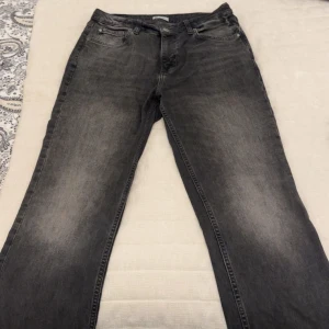 Mörkgrå raka jeans - Snygga mörkgrå jeans med raka ben och klassisk femficksdesign. Jeansen har en lätt tvättad look och är tillverkade i robust denim. Passar dig som gillar en enkel och stilren vibe med lite edge.