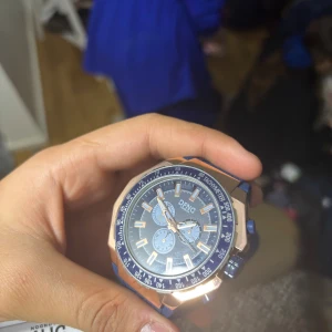 Blå och guld klocka från DFNC - Snygg klocka från DFNC med blå urtavla och guldiga detaljer. Klockan har en robust, sexkantig boett i guldton och blå silikonarmband med cool struktur. Urtavlan har flera små visare och tachymeter runt kanten. Perfekt för dig som gillar sportig och modern stil.