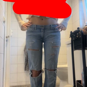 Ljusblå ripped jeans straight fit - Säljer ett par ljusblå jeans med raka ben och slitna detaljer över knän och lår. Jeansen har klassisk femficksdesign och låg midja. Perfekt för dig som gillar en avslappnad och trendig look.