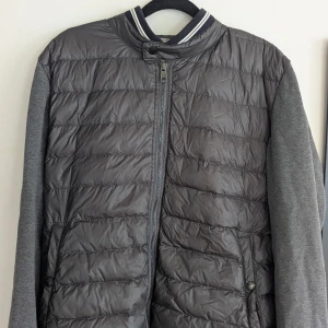 Grå Moncler cardigan XL - Snygg grå cardigan från Moncler i storlek XL. Säljs då jag fick den som gåva men är för stor för mig. Använd ett fåtal gånger. Sitter bra längdmässigt men är för bred. Är 185 och väger 72 kg.