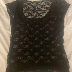 Svart spetsblus från Brandy Melville - Supersnygg svart blus från Brandy Melville i genomskinlig spets med blommigt mönster. Är onesize men passar som S.