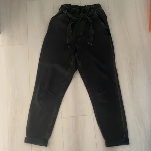 Svarta relaxed high waist jeans  - Svarta jeans från HM (tror jag) med hög midja. Byxorna har resår i midjan, knytband och raka ben med uppvikta benslut. Två fickor fram och två bak. Perfekta för en chill och avslappnad stil.