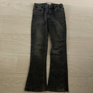 Mörkgrå bootcut jeans Gina Tricot 158 - Mörkgrå jeans från Gina Tricot i storlek 158. Modellen har bootcut-ben och råa, fransiga benslut för en cool look. Jeansen har klassisk femficksdesign och är tillverkade i ett stretchigt denimtyg som sitter snyggt. 