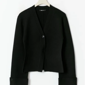 Knitted sculptured cardigan  - Stilren svart kofta från Gina Tricot med v-ringning och två knappar framtill. Koftan har långa ärmar med breda muddar och en rak, något croppad passform. Perfekt att slänga över en t-shirt eller linne för en clean look. Helt slutsåld, aldrig andvänd ❤️❤️