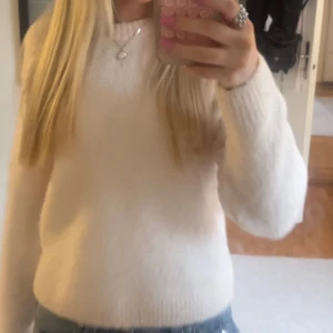 Ljus rosa  lurvig stickad tröja - Mysig lurvig rosa stickad tröja med rund hals och långa ärmar. Perfekt att matcha med jeans för en enkel och stilren look. Tröjan har en klassisk passform och ribbade muddar vid ärmslut och nederkant.