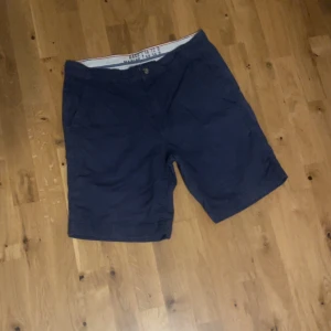 Mörkblå bomullsshorts - Snygga mörkblå shorts i mjuk bomull med klassisk passform och knappstängning fram. Perfekta för varma dagar och enkla att matcha med t-shirt eller skjorta. Shortsen har sidofickor och är midwaist.