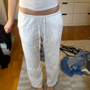 Vita linnebyxor med snörning - Snygga och luftiga vita linnebyxor med avslappnad passform och dragsko i midjan. Perfekta för varma dagar och ger en chill vibe. Byxorna har raka ben och elastisk midja för extra komfort.