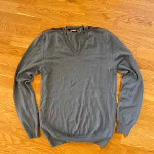 Blå v-ringad tröja från Burberry  - Snygg blå v-ringad tröja från Burberry i storlek L men passar även M. Otroligt skön tröja som passar till allt och är perfekt till hösten. Skriv gärna vid frågor!