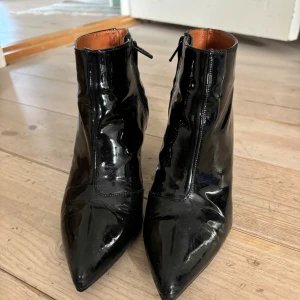 Svarta lackade stövletter Twist & Tango - Snygga svarta stövletter i lackat skinn från Twist & Tango. Modellen har spetsig tå, smal klack och dragkedja på sidan. 