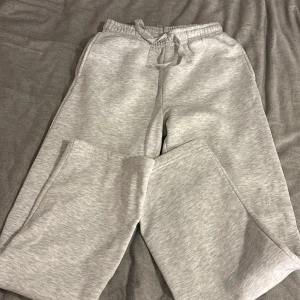 Grå mjukisbyxor från Gina Tricot S - Superbekväma ljusgrå mjukisbyxor från Gina Tricot, basically basics-kollektionen. De har resår och snörning i midjan samt raka ben. Perfekta för chill dagar eller när du vill vara extra comfy. Tillverkade i mjuk bomullsblandning.