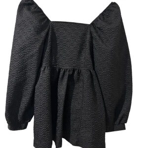 Svart blus med puffärmar och knyt - Säljer en svart blus med voluminösa puffärmar och snygg struktur i tyget. Blusen har en fyrkantig urringning och knytband i ryggen för extra detalj. Materialet är lätt skimrande och ger en cool vibe. 