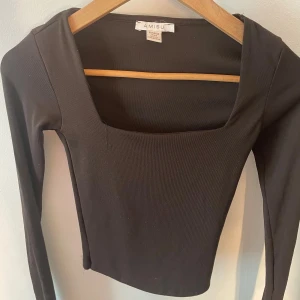 Svart croppad topp från Amisu - Säljer en svart långärmad croppad topp från Amisu med fyrkantig ringning. Toppen är i stretchigt material och har en tight passform som framhäver siluetten. Perfekt att styla med höga jeans eller kjol för en trendig look. 
