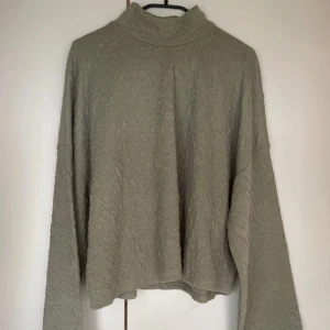 Polotröja med struktur - Säljer en polotröja med lång ärm och snyggt strukturerat tyg. Tröjan har en lös passform och hög krage som ger en chill vibe. Perfekt för lager-på-lager och passar till både jeans och kjol. Svår att få rättvis färg på bild khaki/oliv/mint