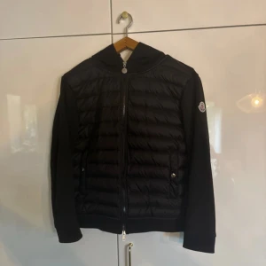 Svart Cardigan Moncler jacka - Perfekt inför vintern❄️⛄️ | Kvitto finns 🧾💛Svart pufferjacka från Moncler med quiltad front, huva och dragkedja hela vägen. Jackan har Moncler-logga på ärmen och är tillverkad i dun och polyester. Snygg och stilren modell som passar perfekt till höst och vinter.